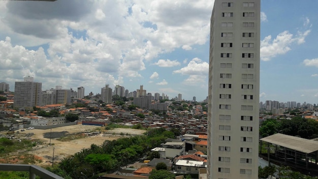 A panoramic view of a densely populated urban area in Brazil, showing residential buildings, schools, and public transportation. The image highlights the importance of census data in urban planning and resource allocation in the community.