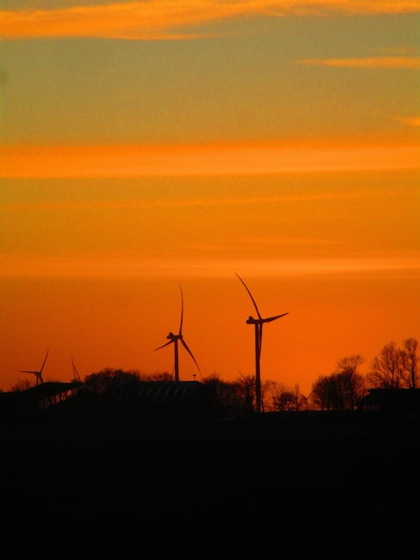 A modern wind farm with tall turbines silhouetted against the setting sun, symbolizing the growth and potential of wind energy in Brazil. Focus on the sleek design of the turbines and the golden light of the sunset.