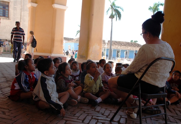 A classroom scene in Brazil, with the teacher interacting closely with a student who looks distressed. The teacher is kneeling to be at the student's level, offering comfort and support. Other students are looking on with concern. The atmosphere is supportive and empathetic, capturing the importance of emotional support in preventing school dropout.