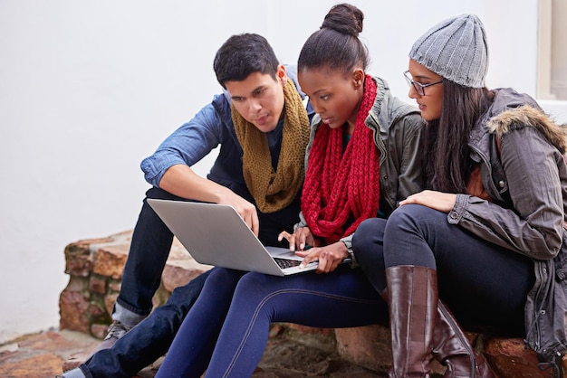 A diverse group of high school students working collaboratively on a project using laptops and interactive displays in a makerspace environment, illustrating the use of technology in project-based learning and fostering teamwork and innovation.