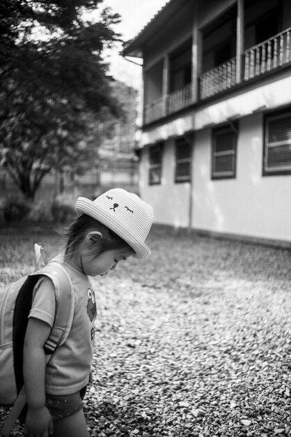 A black and white photograph of a bustling public school in a Brazilian favela, showing children of various ages playing in the schoolyard with limited resources.