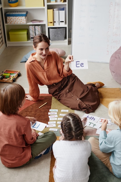A close-up shot of a teacher interacting with a small child during a learning activity in a kindergarten classroom. The focus is on the child's engagement and the teacher's supportive guidance.