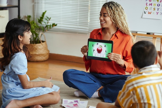 A teacher using a tablet to engage with students, showcasing apps and interactive educational software in a bright classroom.
