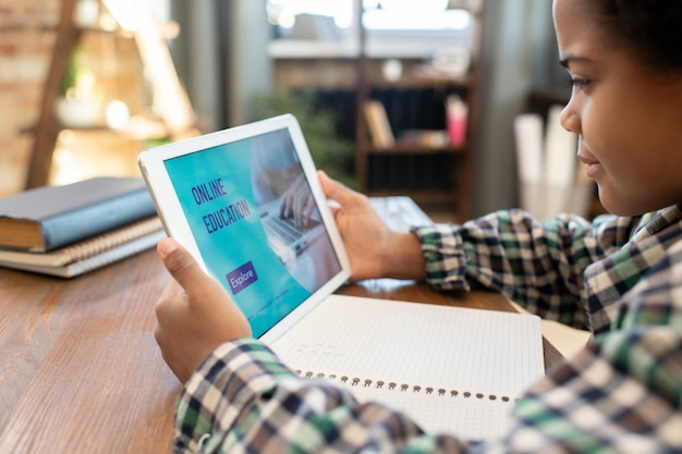 A student using an AI-powered tablet in a modern classroom, with interactive learning applications and personalized feedback appearing on the screen. Focus on engagement and individualized learning.