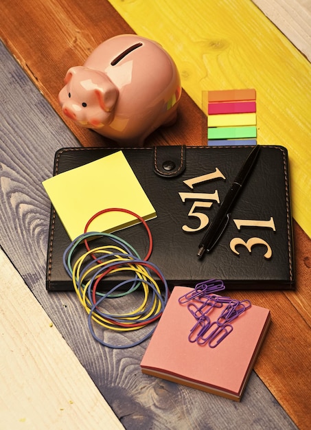 An arrangement of various financial tools, including a calculator, a notepad with financial calculations, coins, and a miniature house, symbolic of savings and investment.