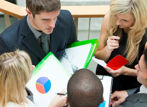 a group of business people sitting around a table discussing economic data, with charts and graphs displayed on a screen, showing a downward trend, indicating concerns about the economic impact of fuel price controls