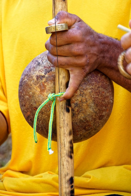 A close-up shot of a berimbau being played, highlighting the instrument's unique construction and the musician's hand movements.