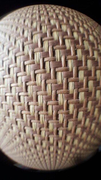 A close-up shot of intricate Indigenous Brazilian basketry, showcasing the textures and patterns created with natural fibers, with a contemporary design item incorporating similar techniques in the background.