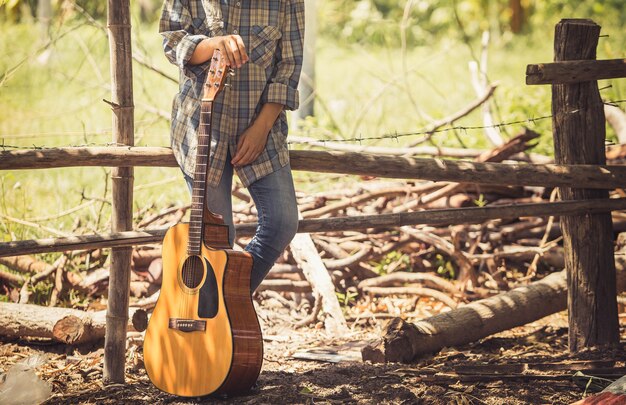 An image depicting a rural scene with a guitar leaning against a wooden fence, symbolizing the connection between sertanejo music and the countryside life in Brazil.