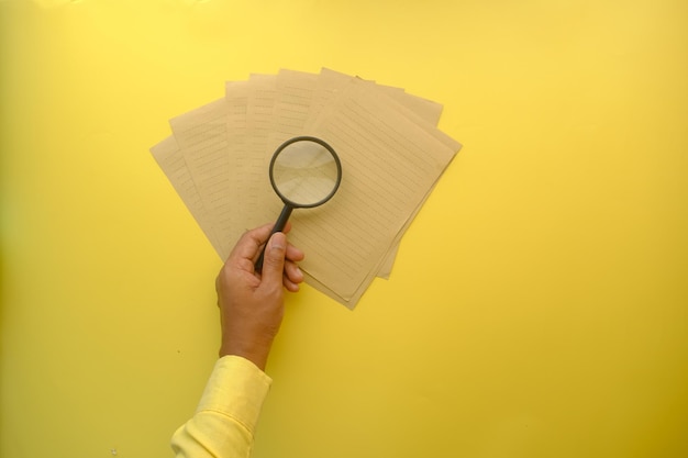 A close-up of a hand holding a magnifying glass over a document titled