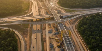 Vista aérea de um complexo projeto de infraestrutura de transporte no Brasil, com rodovias e ferrovias em construção.