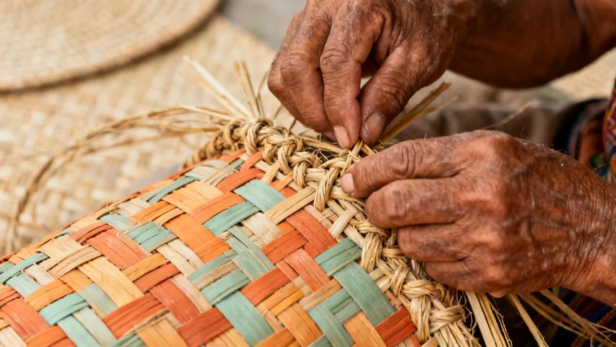 Mãos de um artesão indígena tecendo uma cesta com fibras naturais, demonstrando técnicas ancestrais.